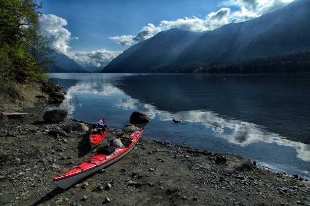 Two red canoes by mountain lake Maple Ridge, British Columbia,Canada - May 2, 2015: Two red canoes seen by Alouette Lake in the Golden Ears Provincial park on a sunny morning. alouette lake stock pictures, royalty-free photos & images