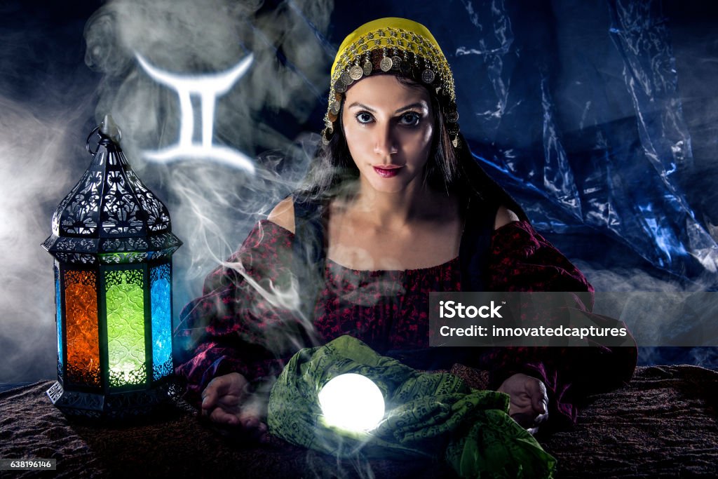 Gemini Horoscope Zodiac Sign with Psychic or Fortune Teller Psychic or fortune teller with crystal ball and horoscope zodiac sign of Gemini, birthdays of May to June. The image depicts astrology in a mystical, esoteric or magical theme composite. Adult Stock Photo