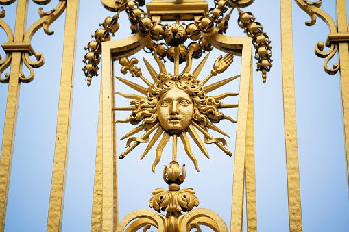 Paris, France - January 7, 2016: Detail of the golden gate of Versailles Palace, on a winter afternoon after its been close for visits. Versailles was a hunting lodge until King Louis XVI transformed it into a palace during the 17th century.