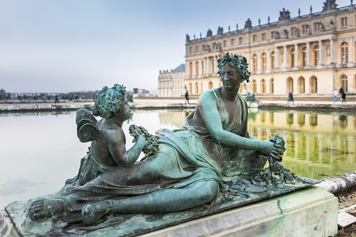 Paris, France - January 7, 2016: Gardens of Versailles Statue on the Water Parterre. Versailles was a hunting lodge until King Louis XVI transformed it into a palace during the 17th century.