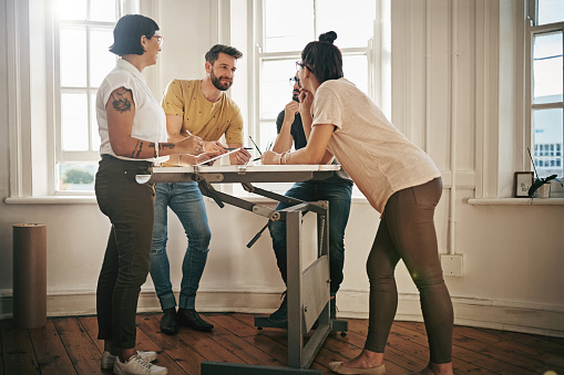Shot of a team of designers brainstorming together around a drafting table