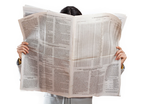 Woman reading newspaper on white background