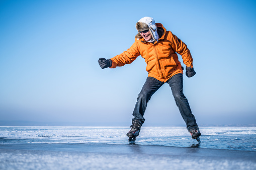 senior man showing his ice skating skills on frozen lake despite his age