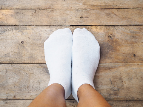 Selfie feet wearing white socks on wooden floor background