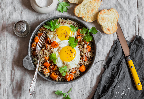 Roasted sweet potato, quinoa and fried egg bowl. Delicious healthy breakfast or lunch. Top view