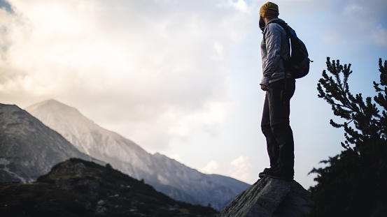 Traveler with backpack looks on a mountain peak in front of him.