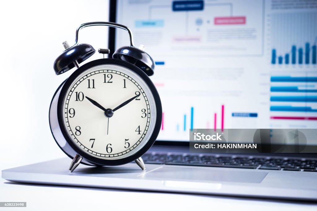 Alarm clock with stock graph chart in laptop screen background. Alarm clock with stock graph chart in laptop screen background.Time,stock market,business success and investment concept.Alarm clock with stock graph chart in laptop screen background.Time,stock market,business success and investment concept. Time Stock Photo