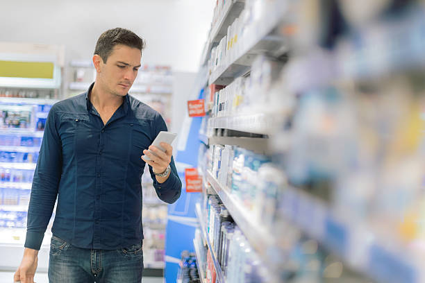 mann mit smartphone im supermarkt - shelf pharmacy people indoors stock-fotos und bilder