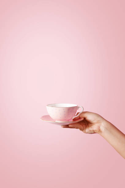 mujer con la mano sosteniendo una taza de té sobre fondo pastel - tea cup fotografías e imágenes de stock