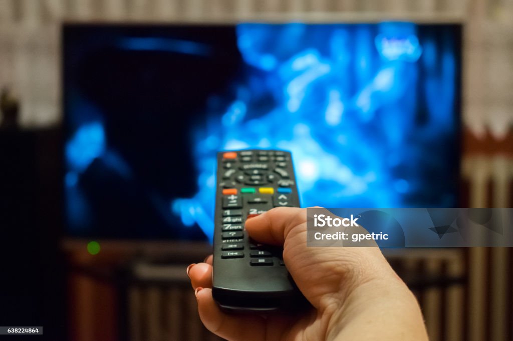 Regarder la télévision et utiliser la télécommande - Photo de Télévision libre de droits