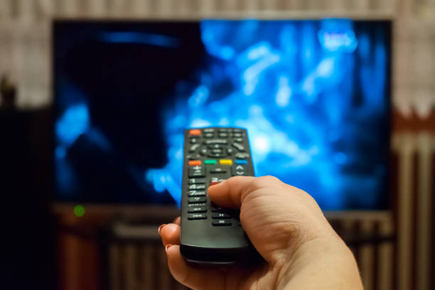 watching tv and using remote control - changing channels imagens e fotografias de stock