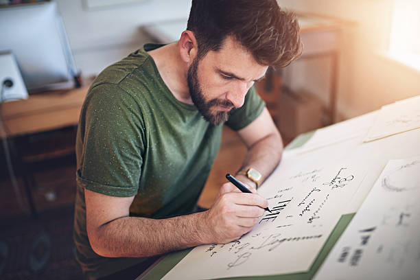 Good typography can add tremendous power to your design Shot of a young designer working on his drafting table graphic designer photos stock pictures, royalty-free photos & images