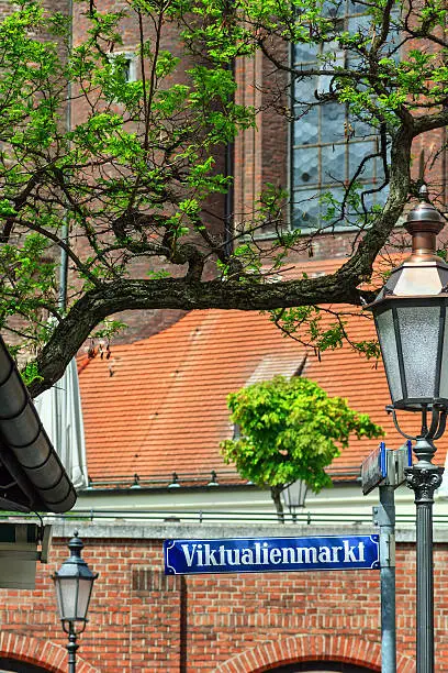 Munich Street Sign: Viktualienmarkt (The famous "Victuals Market" in the centre of Munich). In the Background the Church "St. Peter, called Old Peter - the oldest parish church in Munich, Upper Bavaria, Bavaria, Germany). Selective Focus. Focus on the street sign.