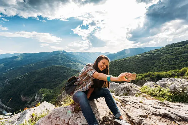 Photo of Tourist taking selfie on the top of the mountain