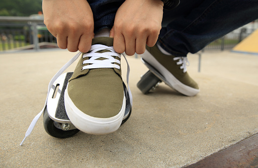 freeline skateboarder tying shoelace at skatepark ramp