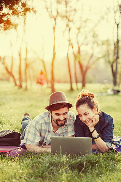 도시 공원에서 무릎 상단을 가진 젊은 부부 - laptop computer grass nature 뉴스 사진 이미지