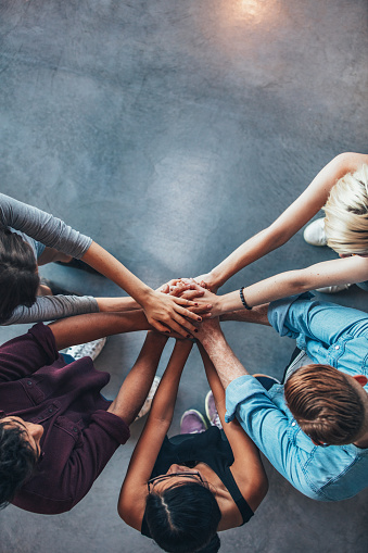 Top view shot of stack of hands. Young college students putting their hands on top of each other symbolizing unity and teamwork.