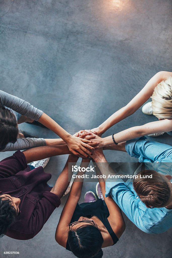 Stack of hands symbolizing trust and cooperation Top view shot of stack of hands. Young college students putting their hands on top of each other symbolizing unity and teamwork. Teamwork Stock Photo