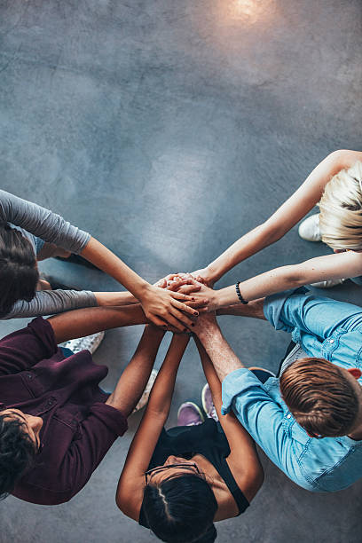 Stack of hands symbolizing trust and cooperation Top view shot of stack of hands. Young college students putting their hands on top of each other symbolizing unity and teamwork. jacob ammentorp lund stock pictures, royalty-free photos & images