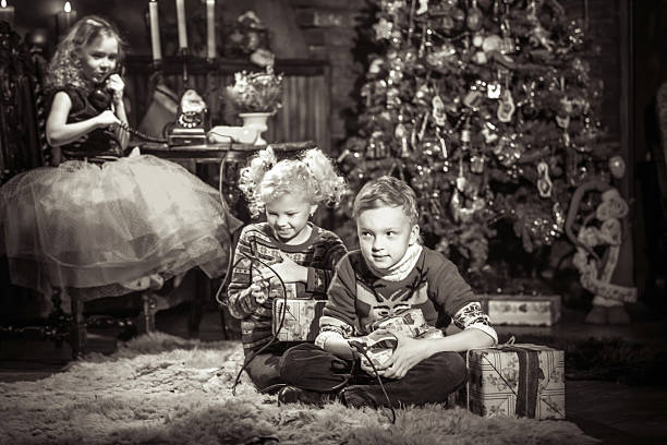Smiling small boy sitting next to Christmas tree with new toys on Christmas morning. Scanned Polaroid print.