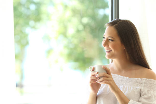 istock Happy girl looking through window tasting coffee 638238548