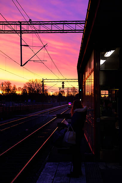 Stockholm, Sweden - November 25, 2016: Outdoor subway train station platform in winter sunrise. Commuter taking picture of fantastic sky. Sollentuna in north Stockholm.