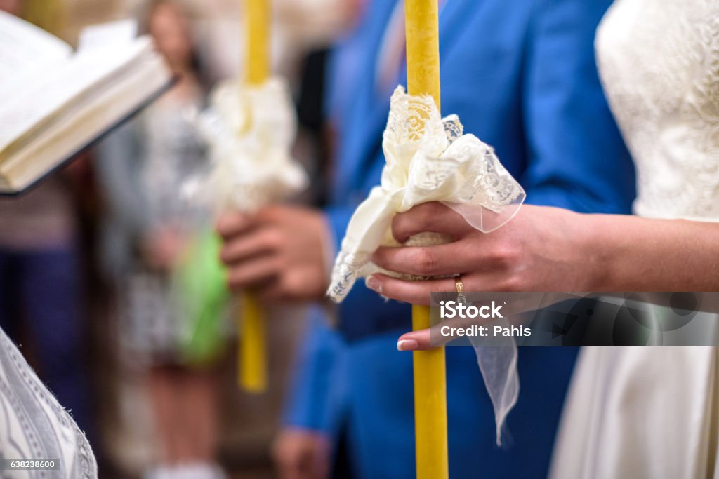 Bride and groom holds candles decorated wtih white flowers Bride and groom holds candles decorated wtih white flowers and ribbons. Adult Stock Photo