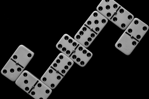 Top view of domino match. Black background, white pieces.