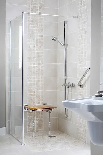 Modern disabled shower cubicle with glass door in luxury bathroom