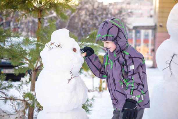 istock Funny little kid boy making a snowman and eating carrot, 638249148