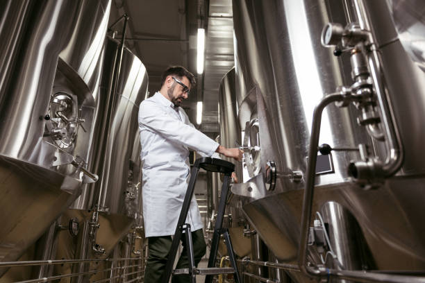 istock Serious man using ladder and brewing mechanism at factory 638253966