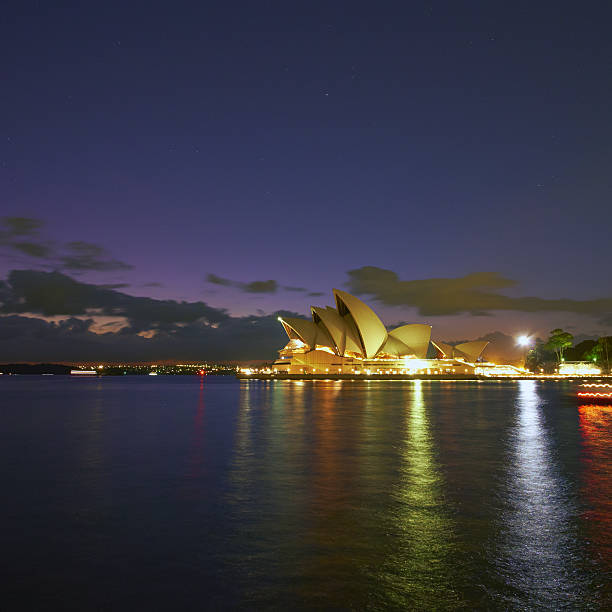 Sydney Australia - April 1, 2016: Pre-dawn in Sydney, and stars twinkle above the iconic (and brightly lit) roof of the city's famous Opera House.