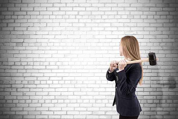 istock Woman crashing white brick wall with sledgehammer 638262226