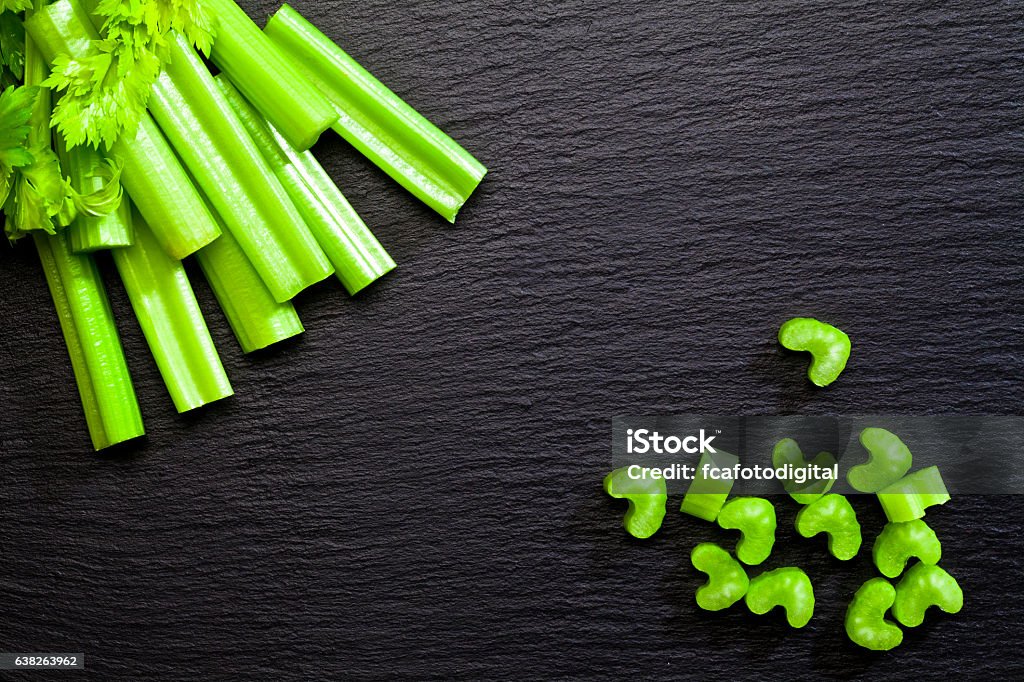 Sticks and chopped celery on dark background Top view of celery sticks and chopped celery on dark slate background with copy space. DSRL studio photo taken with Canon EOS 5D Mk II and Canon EF100mm f/2.8L Macro IS USM Lens Celery Stock Photo