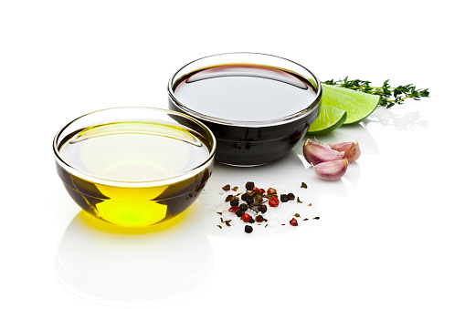 Ingredients for a perfect vinaigrette, olive oil, balsamic vinegar, salt, pepper, garlic and lime isolated on reflective white background. DSRL studio photo taken with Canon EOS 5D Mk II and Canon EF 70-200mm f/2.8L IS II USM Telephoto Zoom Lens