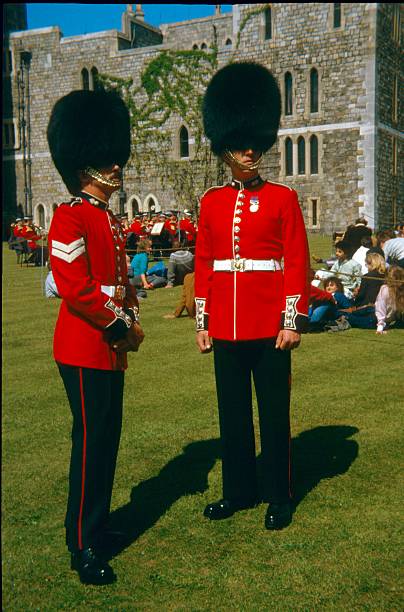 Members of the British Grenadier Guards Berkshire , Windsor,England, UK. - June 8, 1983: Two British Grenadier Gardsman in front of Windsor Castle.Their characteristic sign is the bear fur hat. In the background you can see tourists and spectators, waiting for the change of the Guard in front of Windsor Castle. admired stock pictures, royalty-free photos & images