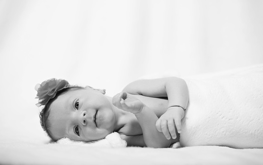 monochrome shot of cute baby girl lying on side and smiling, baby girl portrait.