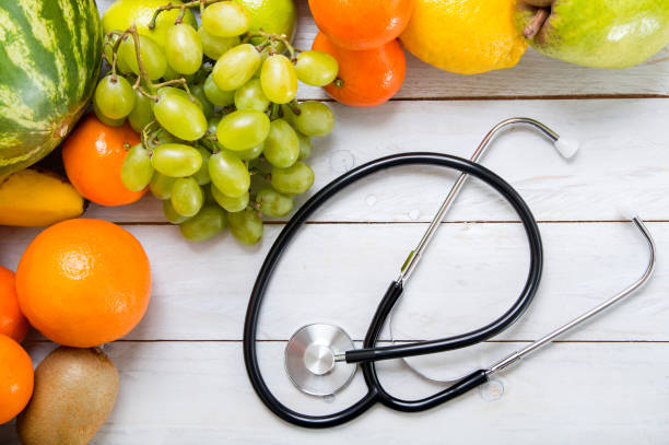 istock Fruits and stethoscope on white wooden table. 638269332