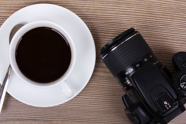 istock Coffee cup and camera on a wooden surface 638273122