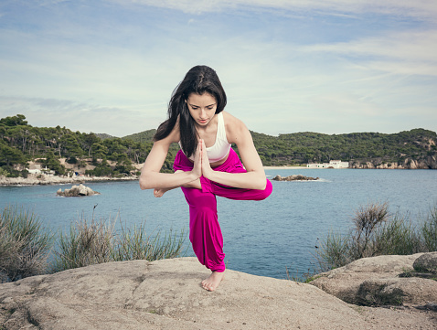 Young woman doing yoga at the sea