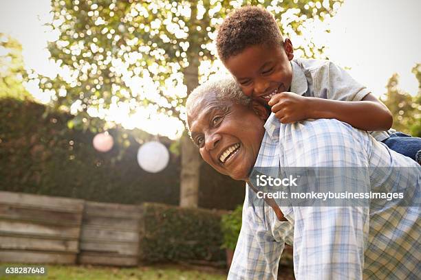 Joven Negro Subiendo A Su Abuelo De Vuelta En El Jardín Foto de stock y más banco de imágenes de Tercera edad