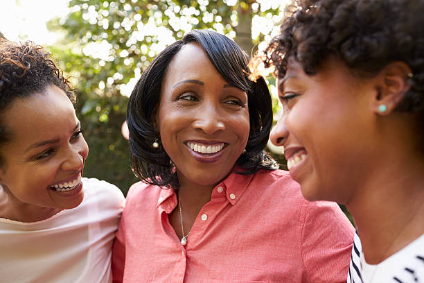 Black mother and two adult daughters in garden, close up Black mother and two adult daughters in garden, close up mom and sister stock pictures, royalty-free photos & images