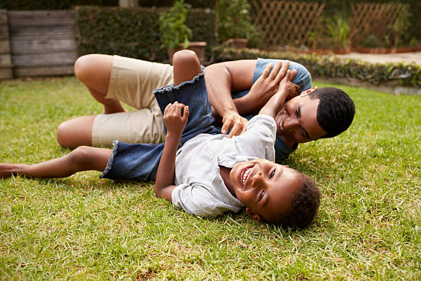 istock Black father and young son play lying on grass, low 638287748