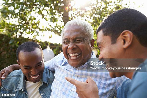 Senior Man Talking With His Adult Sons In Garden Stock Photo - Download Image Now - Senior Adult, Laughing, Father