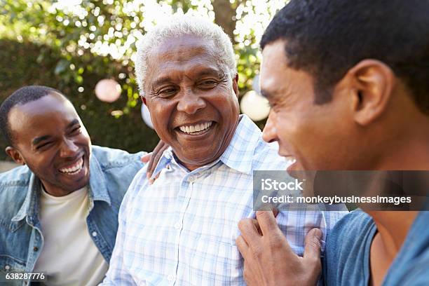 Senior Man Talking With His Adult Sons In Garden Stock Photo - Download Image Now - Senior Adult, Men, Family