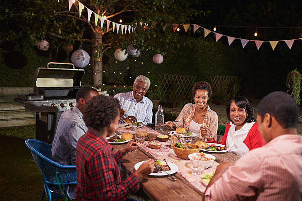 Adult black family enjoying dinner together in their garden Adult black family enjoying dinner together in their garden happy filipino family stock pictures, royalty-free photos & images