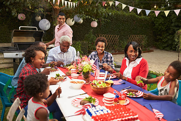 multi generation black family at table for 4th july barbecue - barbecue maaltijd fotos stockfoto's en -beelden
