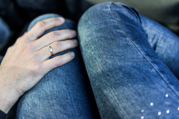 istock Man's hand with wedding ring on woman's legs in jeans 638298672