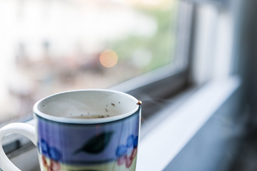 Cup with hot tea and steam on window sill