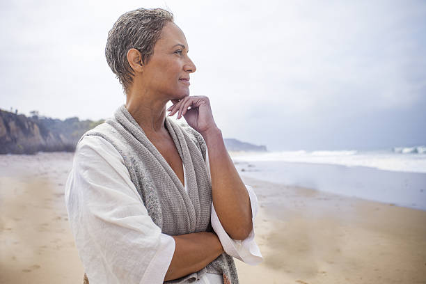 mujer negra mayor relajándose en la playa - reflection women contemplation ethnic fotografías e imágenes de stock